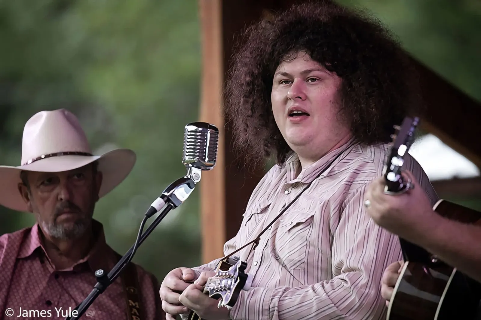 Daniel David singing at a vintage microphone with Mark Krider looking on